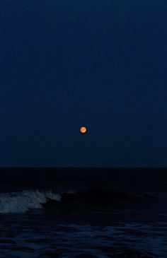 the moon is setting over the ocean with waves