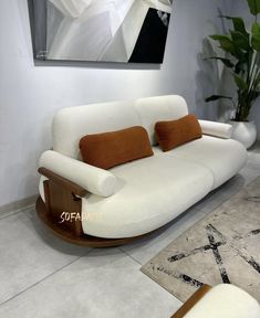 a white couch sitting on top of a floor next to a rug and potted plant