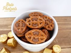 some pretzels are in a white bowl on a wooden table next to gold foil