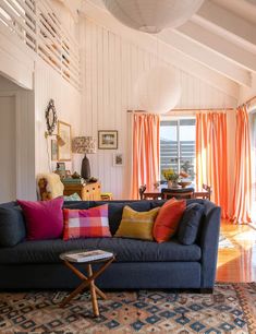 a living room filled with furniture and lots of orange drapes on the windowsill