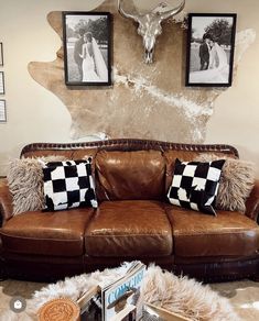 a brown leather couch sitting in a living room next to a cow skull