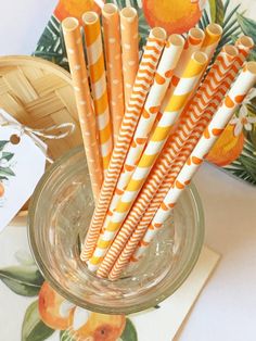 orange and white striped paper straws in a glass bowl on top of a table