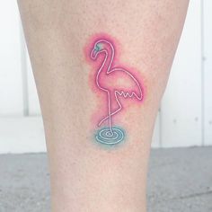 a flamingo tattoo on the leg of a woman's legs with pink and blue ink