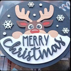 a merry christmas sign hanging from the side of a building with snowflakes on it