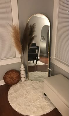 a mirror sitting on top of a wooden floor next to a white bench and ottoman