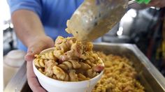 a person pouring macaroni and cheese into a bowl