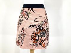 Eye-catching embroidered mini skirt by River Island in soft pink fabric. The skirt features bold Tiger and Floral embroidery on the front. Button fastening. In good condition Measurements: Waist: 28" Length: 17.5" Fitted Embroidered Mini Skirt, Fitted Pink Embroidered Skirt, Pink Embroidered Skirt, Rock River, Pink Mini Skirt, Rose Pale, Embroidered Skirt, Flowers Pink, Pink Mini