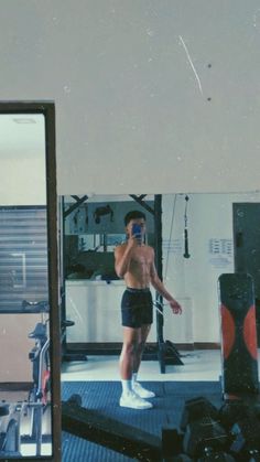 a shirtless man standing in front of a mirror