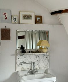 a white sink sitting under a mirror next to a wall mounted faucet in a bathroom