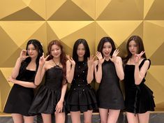 the girls are posing together in front of a gold and black wall with their hands up