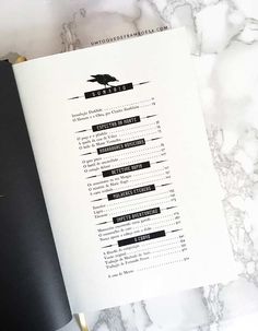 an open book sitting on top of a table next to a black and white menu