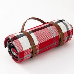 a red and white checkered blanket with brown leather straps on the bottom is folded up