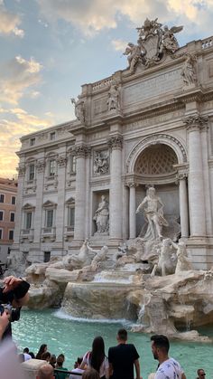 people are taking pictures in front of the trello diosssi fountain at sunset