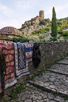 some blankets are hanging on a stone wall