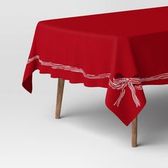 a red table cloth with white lines on it and a bow around the edge,