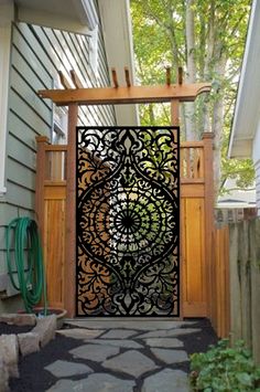 an iron gate with a dragon design on the side of a house in front of a tree