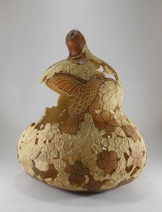 a decorative vase sitting on top of a white table next to a wooden bird figurine