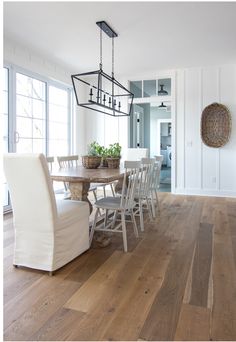 a dining room table with white chairs and wooden floors