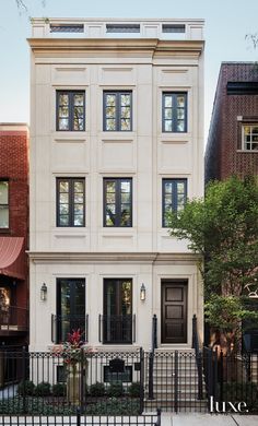 a white two story house with black iron fence