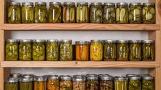 several shelves filled with different types of pickles and other food in glass jars on wooden racks