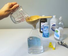 a person is pouring liquid into a measuring cup with a spoon and other items around it