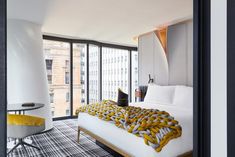 a bed sitting next to a window with a yellow blanket on it's headboard