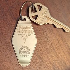 a metal keychain that is on top of a wooden table next to a pair of keys