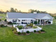 an aerial view of a house with a white picket fence in the foreground and green grass around it