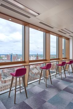 an office with pink chairs and large windows overlooking the cityscape in front of them