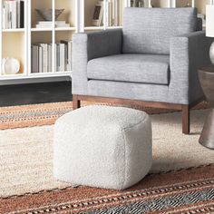 a living room with a chair, ottoman and bookcase in the background on an area rug