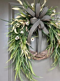 a wreath with black and white ribbons hanging on the front door, decorated with flowers