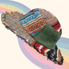 a multicolored hat with fringes is on a rainbow colored striped pattern background