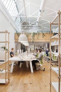 two people sitting at a table in an office with white walls and wood flooring