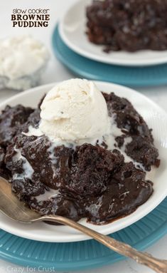 a white plate topped with brownie and ice cream on top of a blue plate