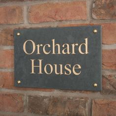 a sign on the side of a brick wall that says orchard house in gold lettering