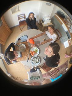 three women sitting at a table with plates of food in front of them looking up