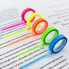 five different colored rings sitting on top of an open book with text in the background