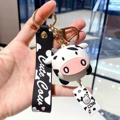 a hand holding a cow keychain with a black and white tag on it