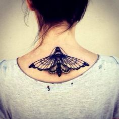 a woman's back neck with a butterfly tattoo on the upper part of her neck