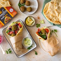 two burritos on plates with dipping sauce and other appetizers next to them