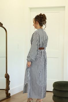 Our Walker Striped Dress is definitely a must-have item! This collarless shirt dress does have working buttons on half of the bodice. It is nursing friendly. This maxi length dress has curved side slits in the hemline which allow for walking room. - Round neckline | Collarless shirt dress - Long sleeve | Elastic cuff - Working buttons on half of bodice | Nursing friendly - Belt detail at waistline - Pockets - Maxi length - Approximately 10.5" side slits at hemline - Material: 100% Cotton Color D Daywear Midi Dress With Button Back, Buttoned Midi Length Maxi Dress For Daywear, Button Back Midi Dress For Daywear, Spring Workwear Maxi Dress With Side Slits, Daywear Maxi Dress With Buttons, Buttoned Maxi Dress For Daywear, Maxi Dress With Asymmetrical Hem For Work In Spring, Belted Maxi Shirt Dress For Work, Maxi Length Belted Shirt Dress For Work