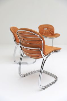 two modern chairs with metal frames and leather seats