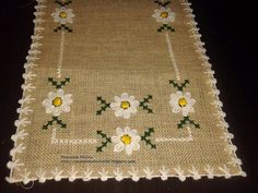 a close up of a table cloth with white flowers and green leaves on the edge