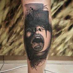 a man's leg with a black and grey tattoo on it that has an image of a woman screaming