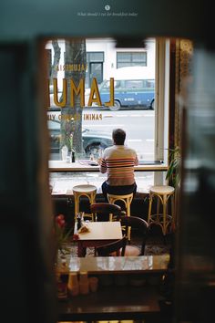 a man sitting at a table in front of a window with the words lamu on it