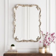 a mirror sitting on top of a wooden table next to a vase with flowers in it