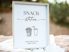 a sign that says snack station on the side of a table with food and drink