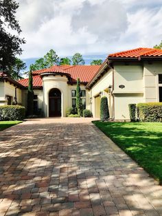 a driveway leading to a large house with red tile roof and white trimmings