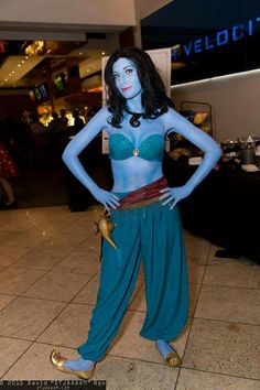 a woman dressed in blue and green poses for the camera with her hands on her hips