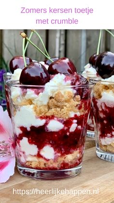 two desserts with cherries and whipped cream are on a table next to flowers